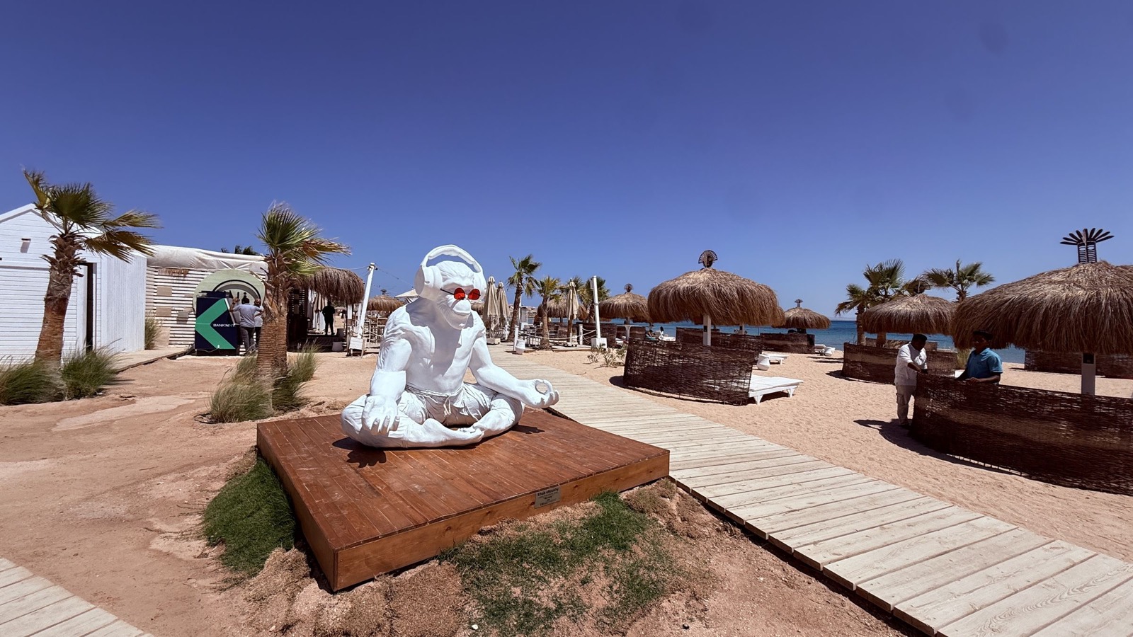 Beach Club mit Statue und Strohschirmen