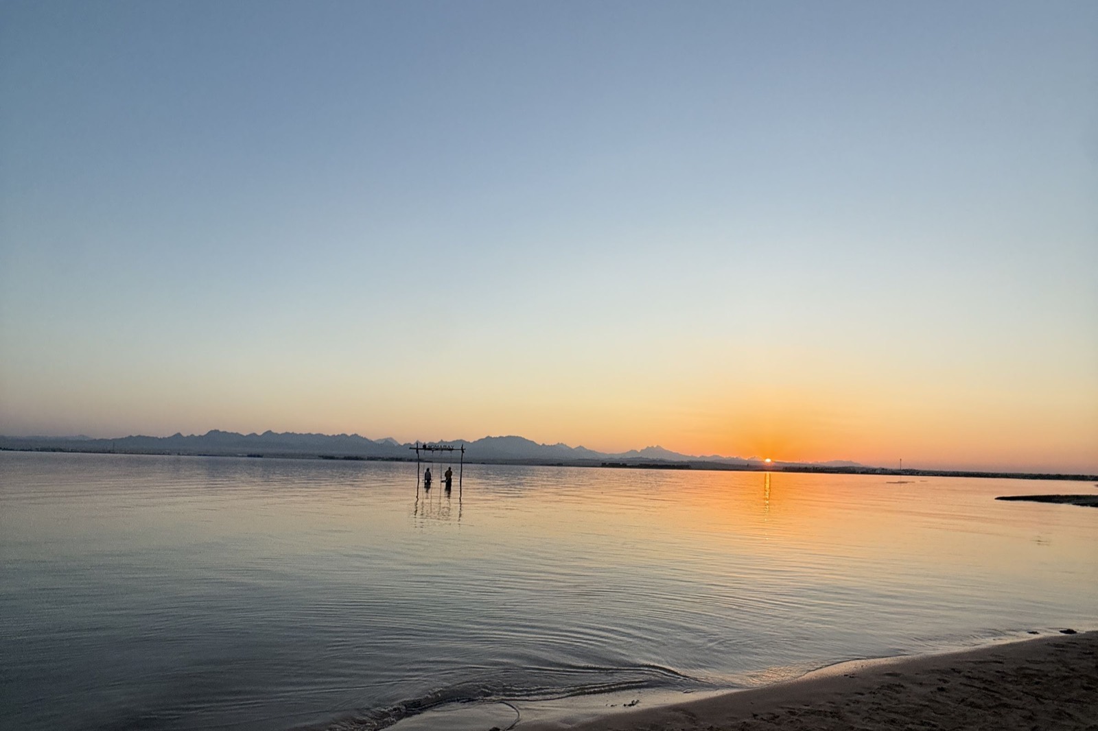 Calm sea at dusk with mountains on the horizon